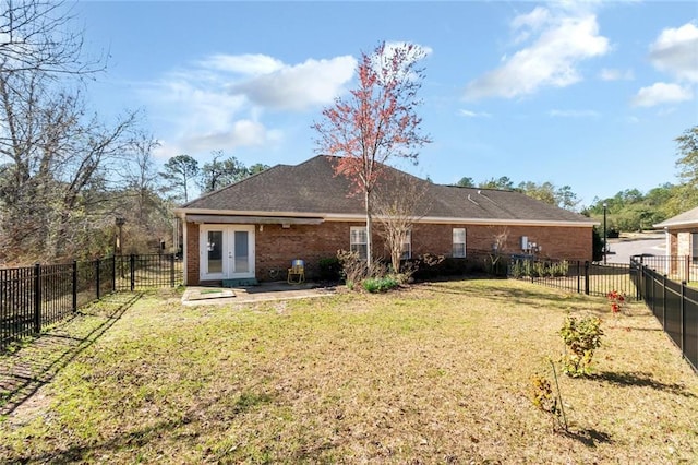 back of property with brick siding, a fenced backyard, a lawn, and french doors