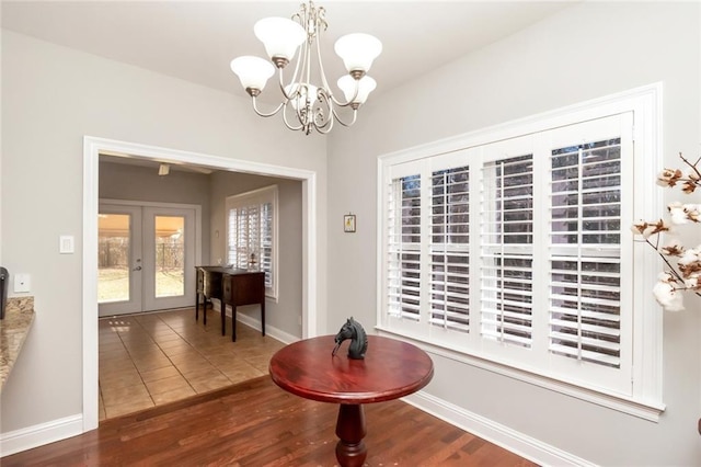 tiled dining room with french doors, baseboards, and an inviting chandelier