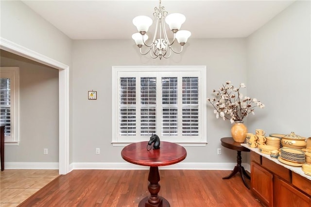 dining space with a chandelier, baseboards, and wood finished floors