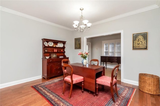 dining room featuring ornamental molding, a notable chandelier, baseboards, and wood finished floors