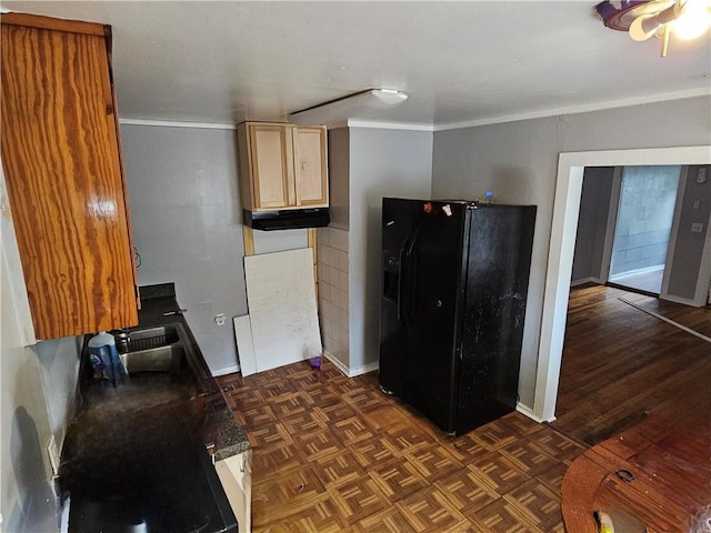 kitchen featuring crown molding, dark countertops, black fridge, under cabinet range hood, and parquet flooring