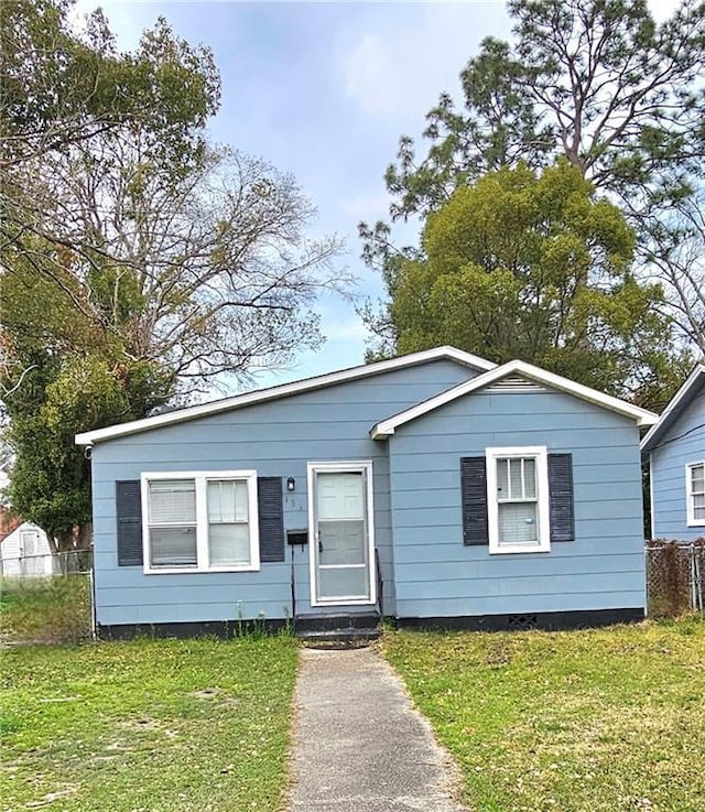 view of front of house with entry steps, fence, and a front lawn