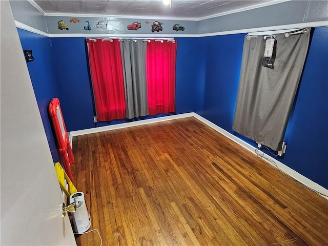 spare room featuring hardwood / wood-style flooring, baseboards, and crown molding