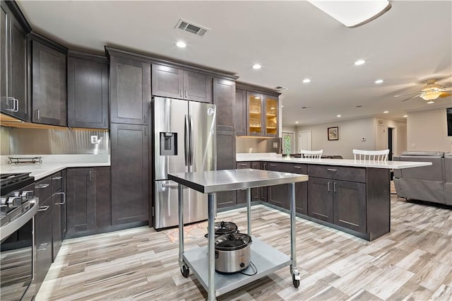 kitchen with light hardwood / wood-style flooring, kitchen peninsula, appliances with stainless steel finishes, dark brown cabinets, and ceiling fan