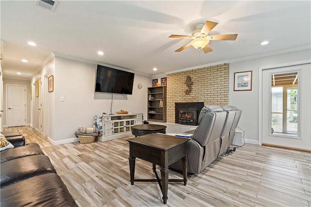 living room with ceiling fan, a brick fireplace, light wood-type flooring, and crown molding