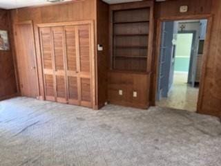 unfurnished bedroom featuring carpet floors and wooden walls