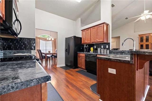 kitchen featuring dark wood-type flooring, high vaulted ceiling, a kitchen breakfast bar, decorative backsplash, and black appliances