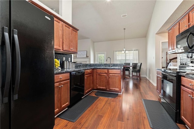 kitchen featuring tasteful backsplash, sink, hanging light fixtures, black appliances, and dark wood-type flooring