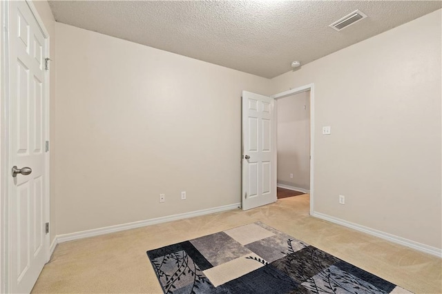 unfurnished bedroom featuring light carpet and a textured ceiling