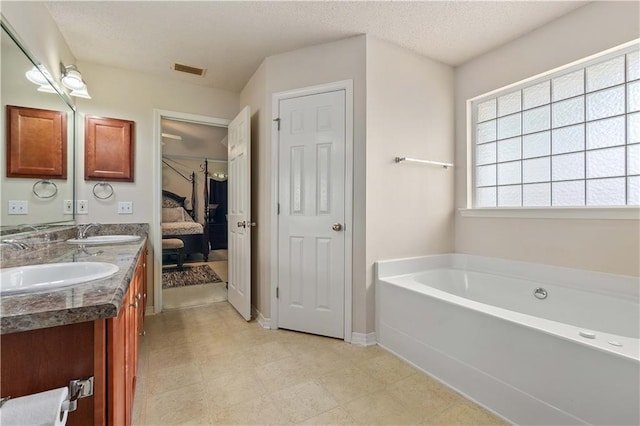 bathroom with vanity, a tub, and a textured ceiling