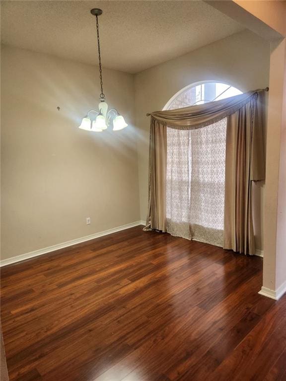 unfurnished dining area featuring dark hardwood / wood-style flooring, a textured ceiling, and an inviting chandelier