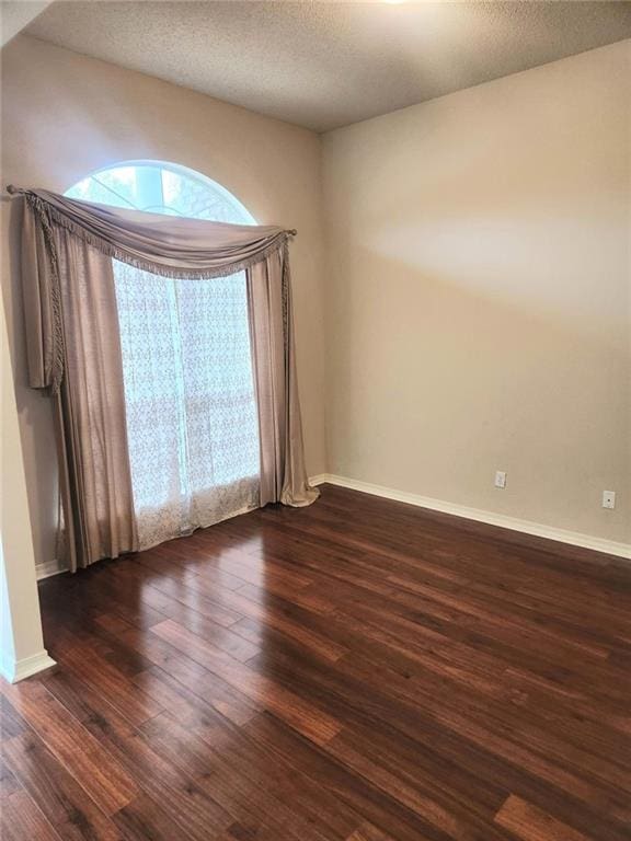 empty room with dark hardwood / wood-style floors and a textured ceiling