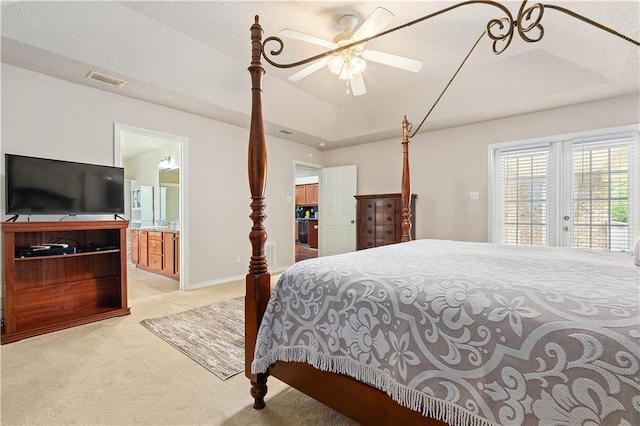 bedroom with ensuite bathroom, light colored carpet, access to outside, a raised ceiling, and ceiling fan