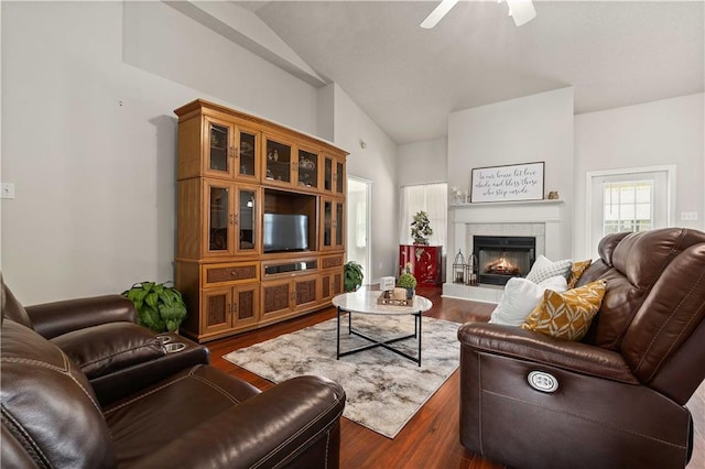 living room with a tile fireplace, vaulted ceiling, dark hardwood / wood-style floors, and ceiling fan