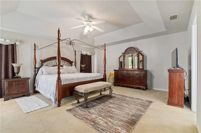 bedroom featuring light colored carpet, ceiling fan, and a tray ceiling