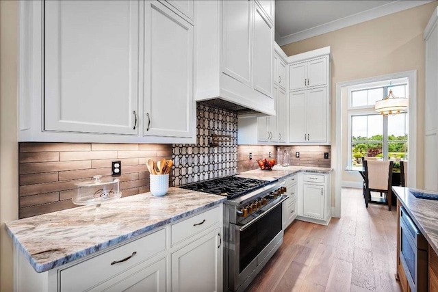 kitchen with light stone countertops, stainless steel appliances, tasteful backsplash, white cabinets, and light wood-type flooring