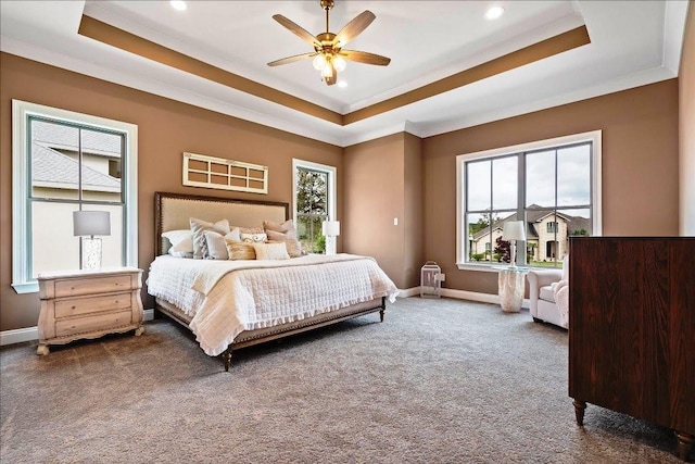 bedroom featuring ornamental molding, dark colored carpet, ceiling fan, and a tray ceiling