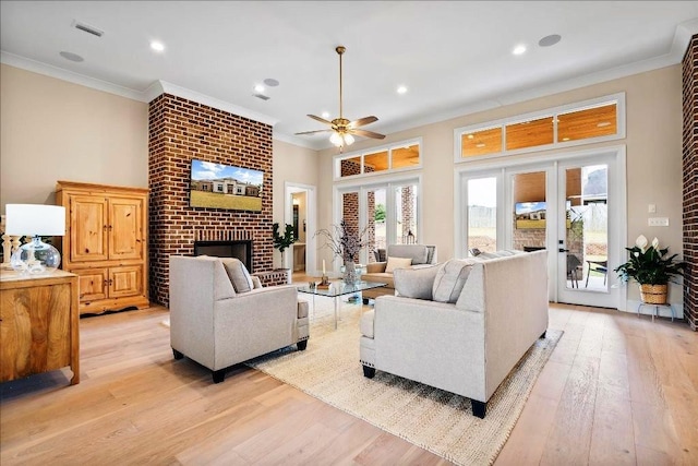 living room with crown molding, light hardwood / wood-style floors, and a brick fireplace