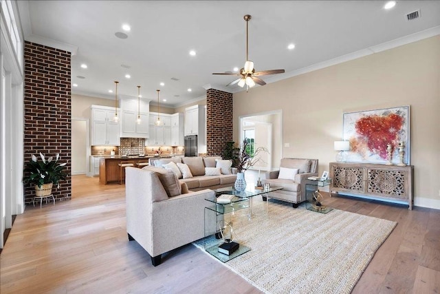 living room with light hardwood / wood-style flooring, ceiling fan, and crown molding