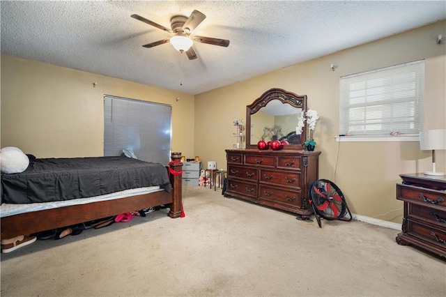 bedroom with ceiling fan, light colored carpet, and a textured ceiling