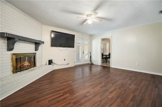 unfurnished living room with ceiling fan, dark hardwood / wood-style floors, a textured ceiling, and a brick fireplace