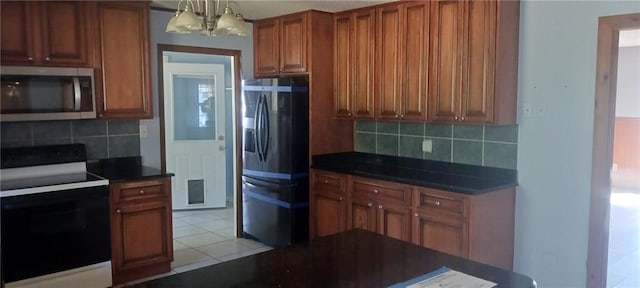 kitchen featuring pendant lighting, appliances with stainless steel finishes, backsplash, and an inviting chandelier