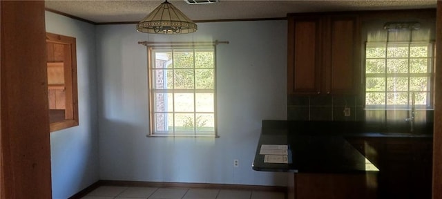 kitchen with an inviting chandelier, a wealth of natural light, decorative light fixtures, and ornamental molding