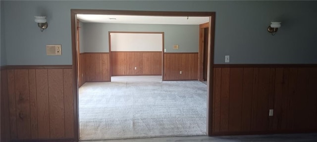 carpeted spare room with wooden walls