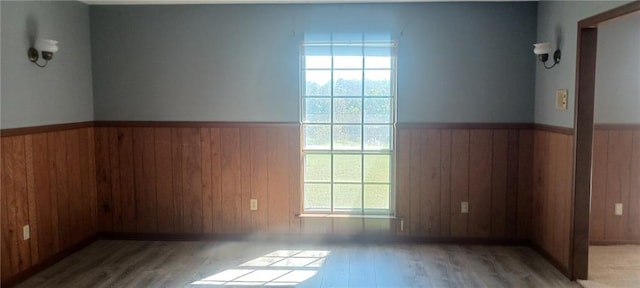 empty room with light hardwood / wood-style floors and wooden walls