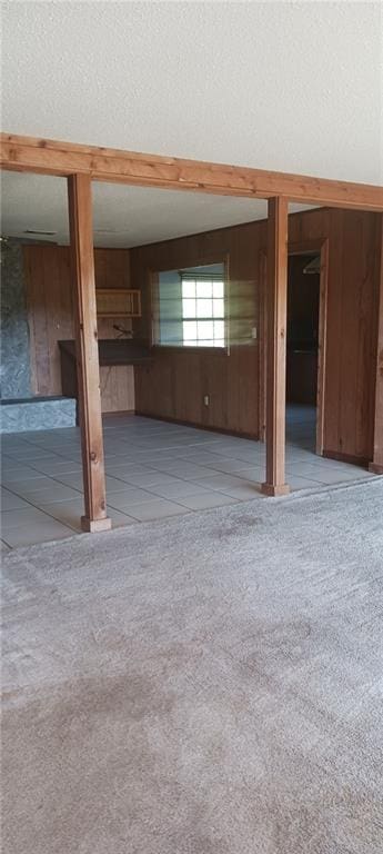 interior space featuring wood walls, a textured ceiling, and light carpet