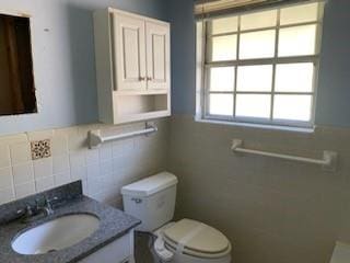 bathroom featuring tile walls, vanity, and toilet