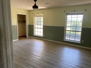 empty room featuring wood-type flooring, a healthy amount of sunlight, and ceiling fan