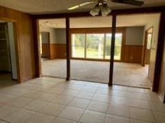 unfurnished room with wood walls and ceiling fan