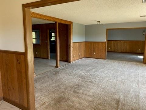 carpeted empty room featuring wood walls and a textured ceiling