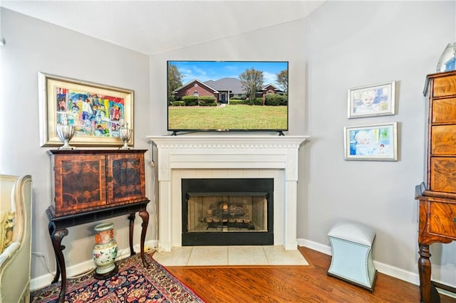 interior space with a tiled fireplace, light hardwood / wood-style flooring, and lofted ceiling