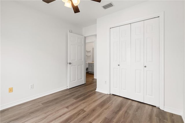 unfurnished bedroom with dark wood-type flooring, ceiling fan, and a closet