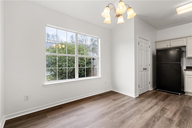 unfurnished dining area with hardwood / wood-style flooring, a healthy amount of sunlight, and an inviting chandelier