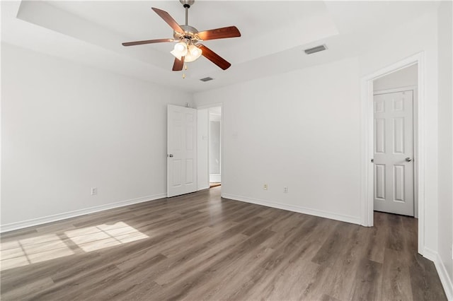 spare room with ceiling fan, dark hardwood / wood-style flooring, and a tray ceiling