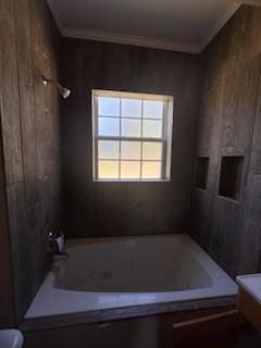 bathroom with bathtub / shower combination, toilet, crown molding, and wood walls