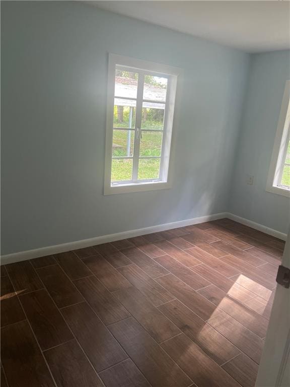 spare room featuring plenty of natural light and dark wood-type flooring