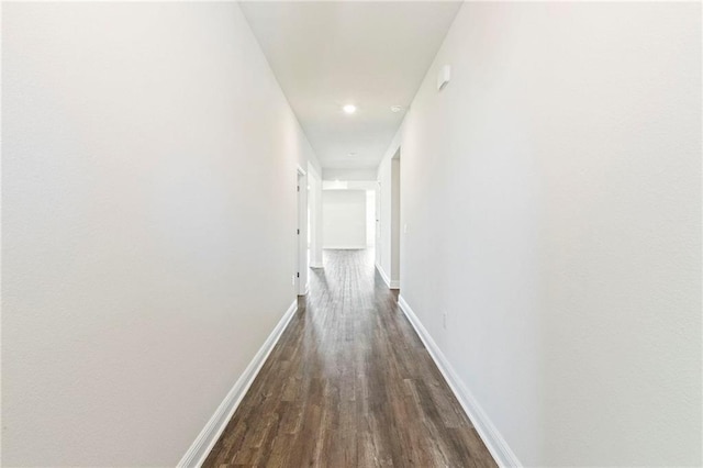 hallway with dark wood-style floors and baseboards