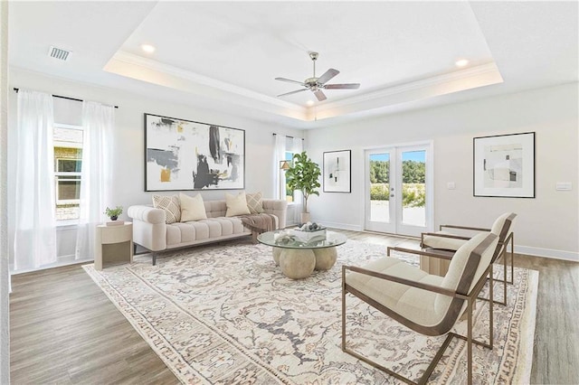 living room featuring a raised ceiling, visible vents, french doors, and wood finished floors