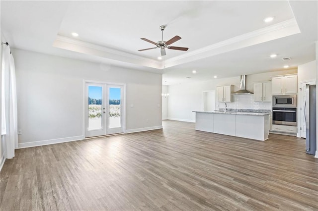 unfurnished living room with a tray ceiling and light hardwood / wood-style flooring