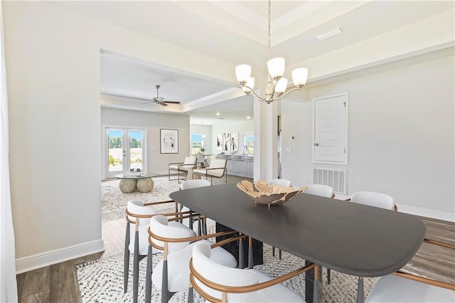 dining space with visible vents, baseboards, a raised ceiling, and wood finished floors