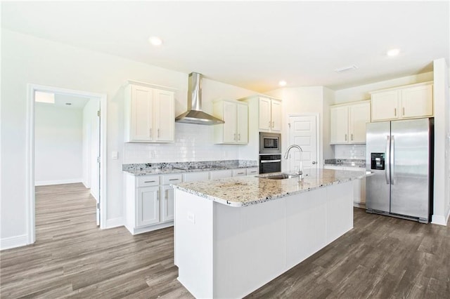 kitchen with stainless steel appliances, a kitchen island with sink, dark hardwood / wood-style floors, wall chimney exhaust hood, and tasteful backsplash