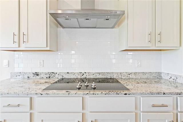 kitchen with light stone counters, black electric cooktop, exhaust hood, and tasteful backsplash