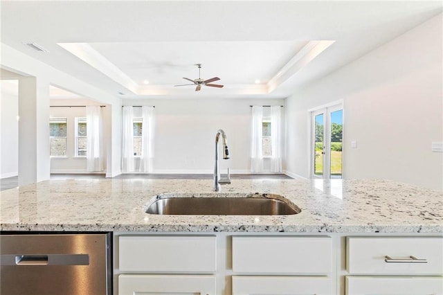 kitchen with white cabinetry, open floor plan, a sink, and a raised ceiling