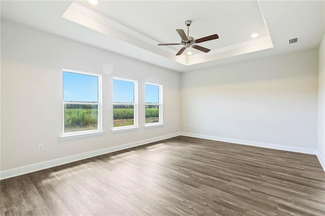 empty room featuring a raised ceiling, ceiling fan, and dark wood-type flooring