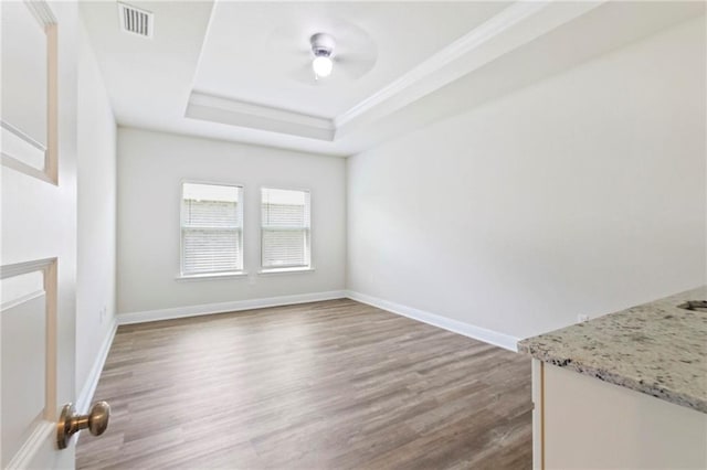 unfurnished dining area with a raised ceiling and wood-type flooring