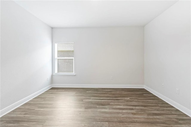 empty room featuring baseboards and dark wood-style flooring